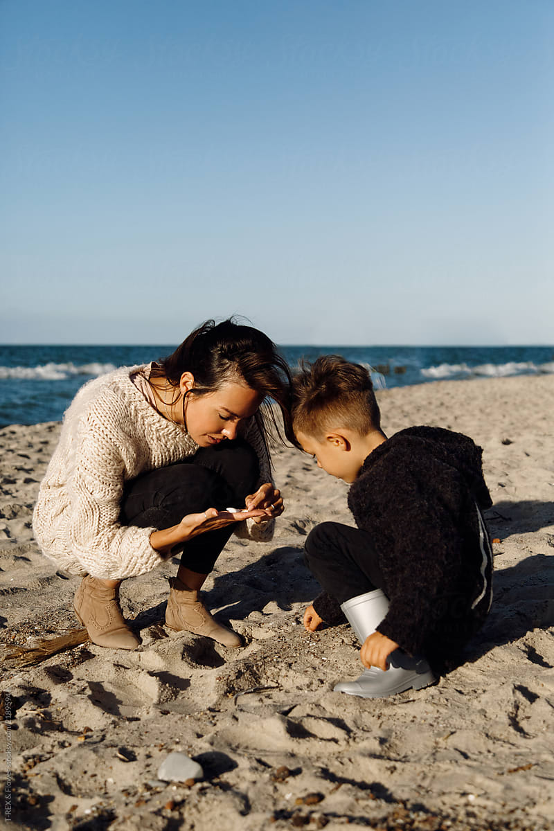 Woman and boy playing in sand at beach