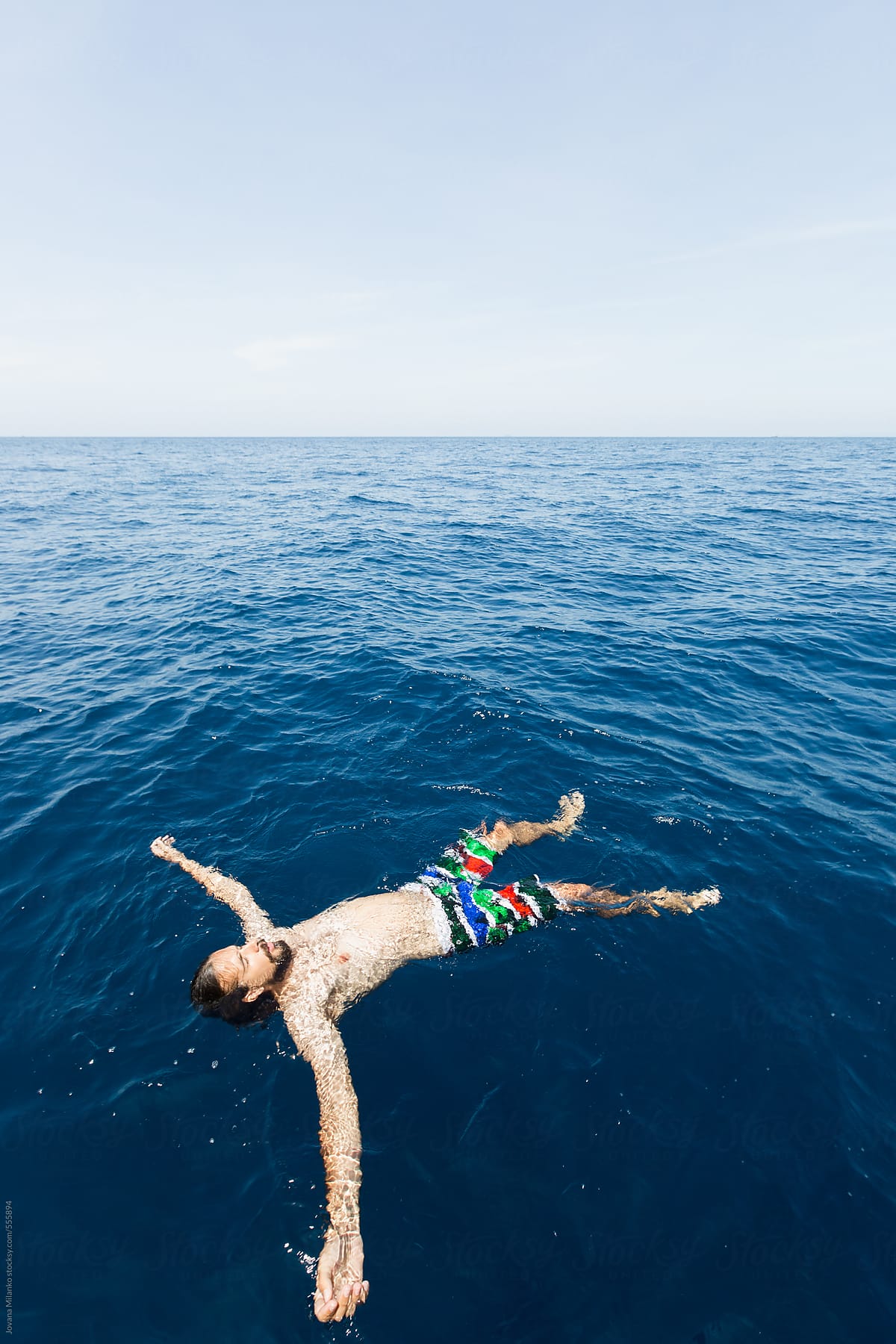 Man Floating With Spread Arms On The Surface Of The Sea Sunbathing