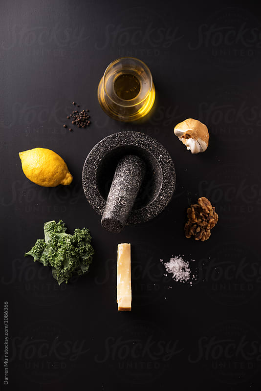 Kale pesto: Ingredients for making kale pesto on a dark background.