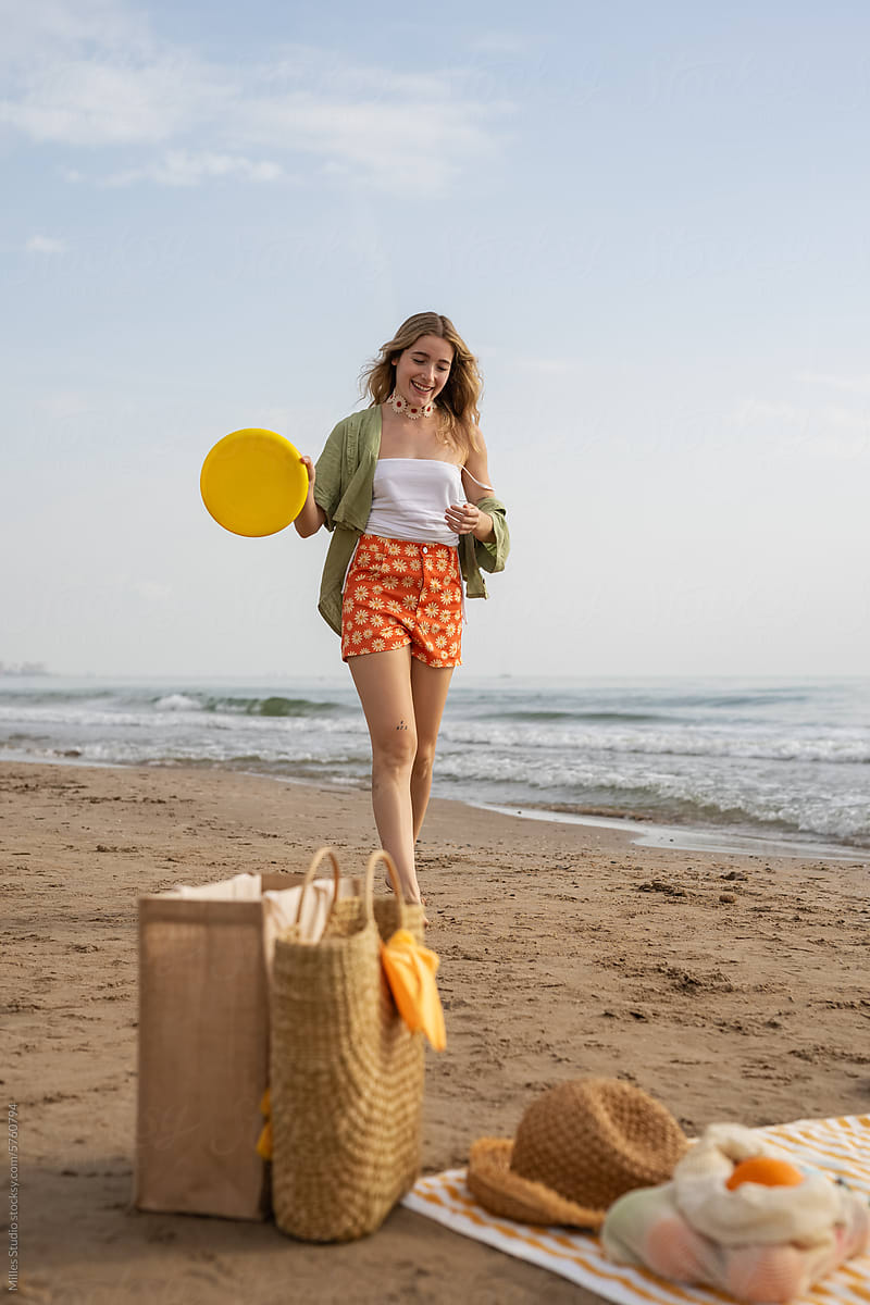 Woman walking with frisbee at sandy beach