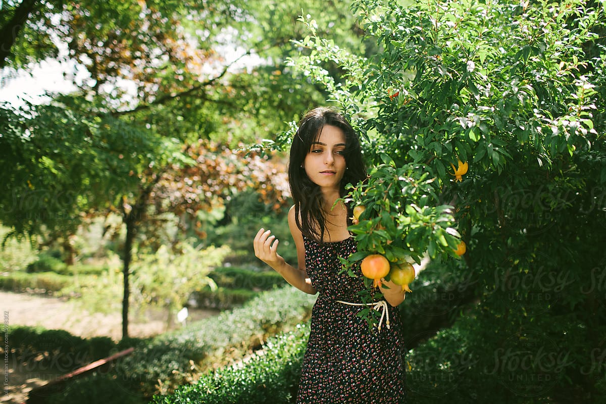 Young woman among raw pomegranates