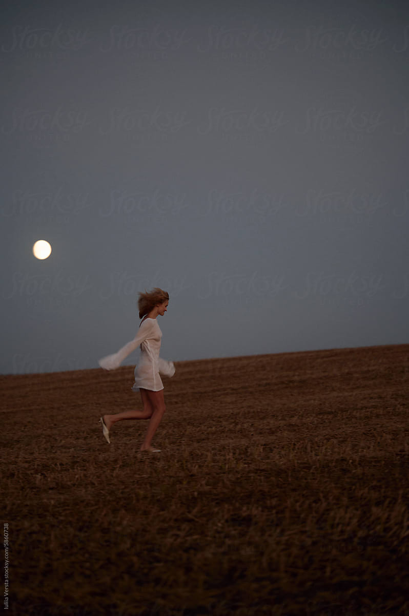 a woman running in the field in the night