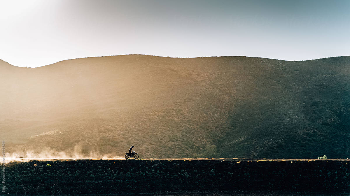Motorcycle rides along a dusty mountain road