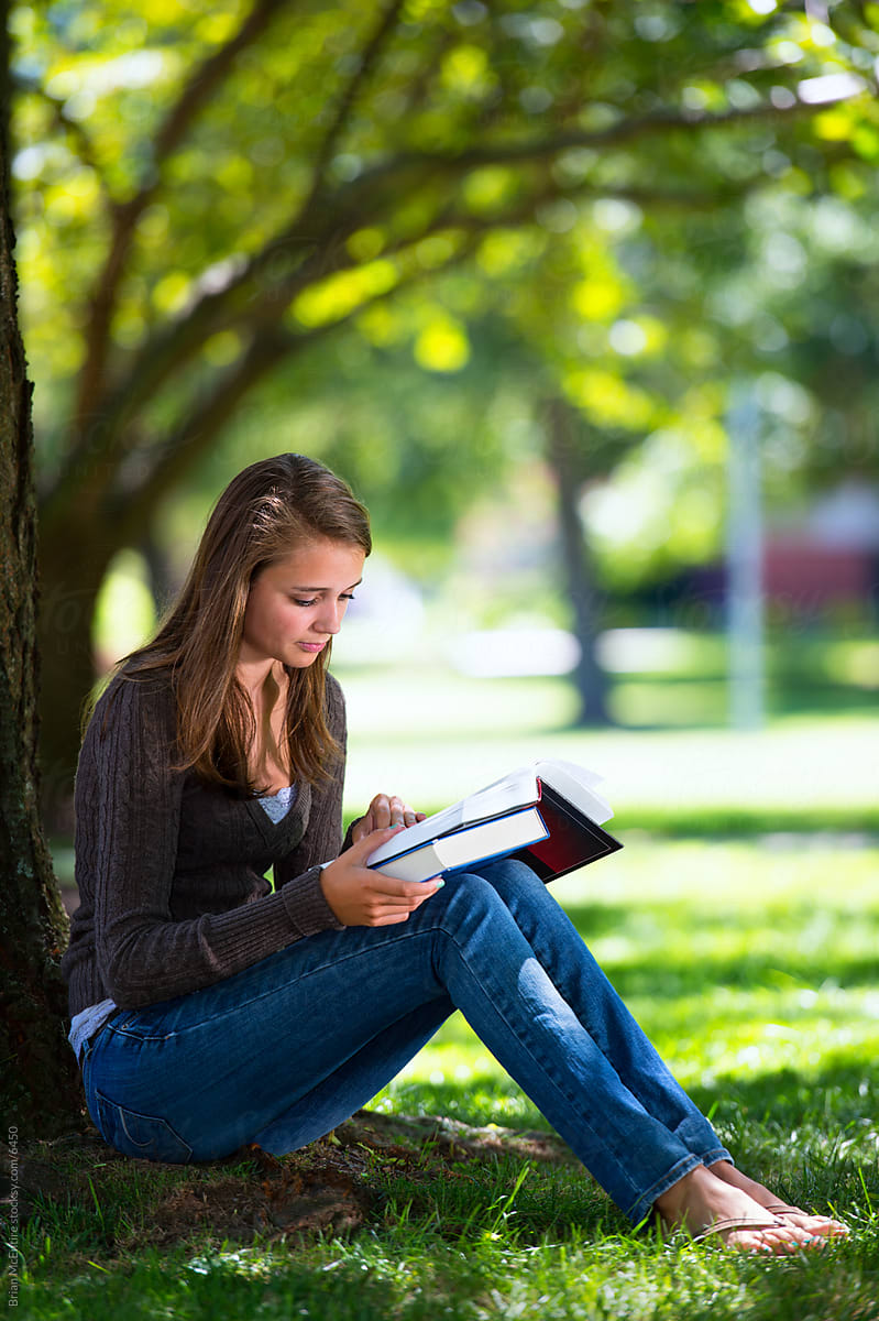 College Freshman Reading Under Tree on Campus