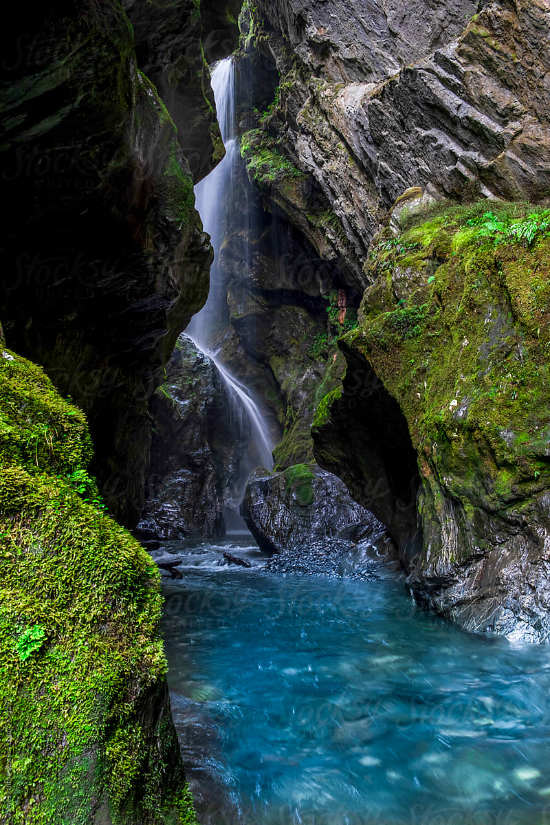 Upright view of Mossy cave with water fall and turquoise water