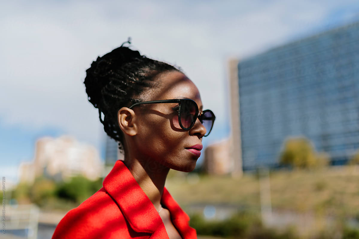 Thoughtful black woman in sunglasses looking away in contrast light