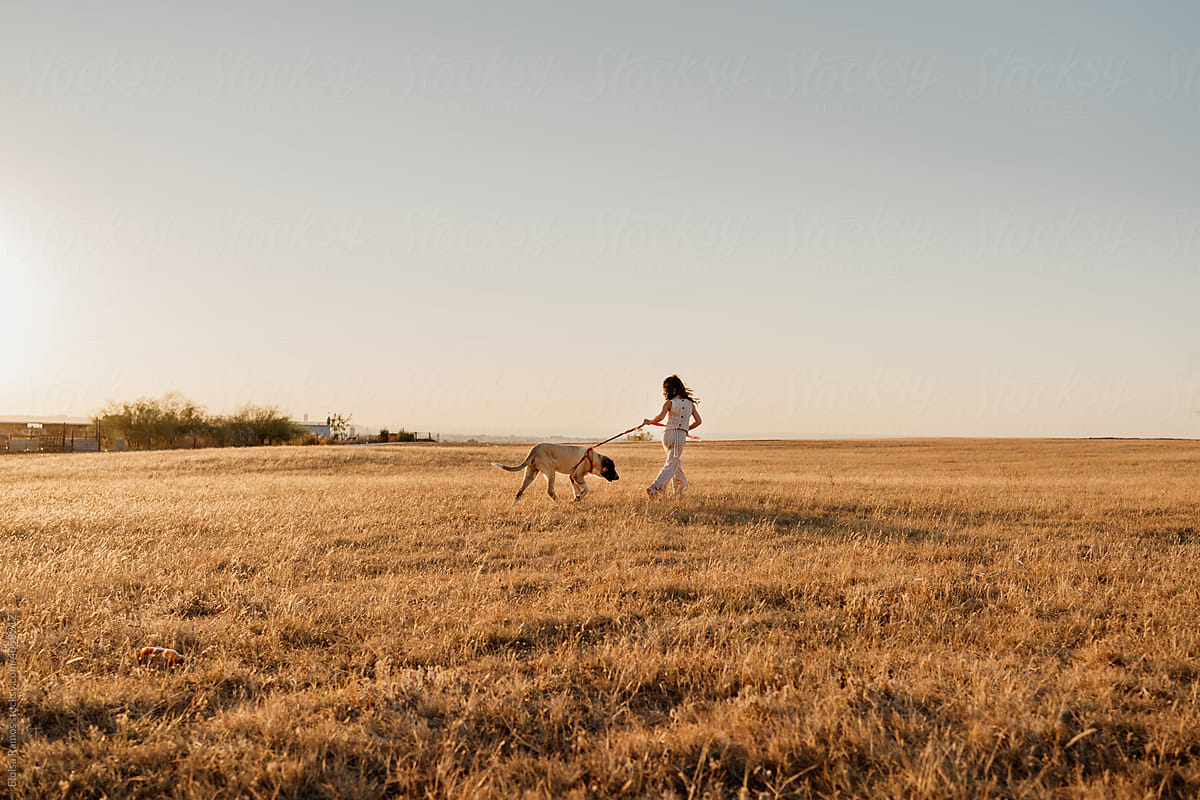 Girl walking her puppy with leash at field