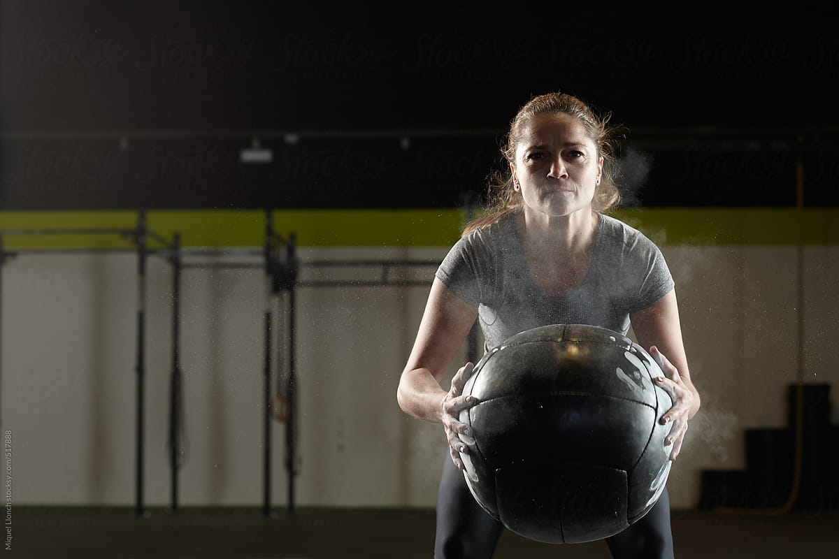 Fit woman holding a heavy training ball in a gym