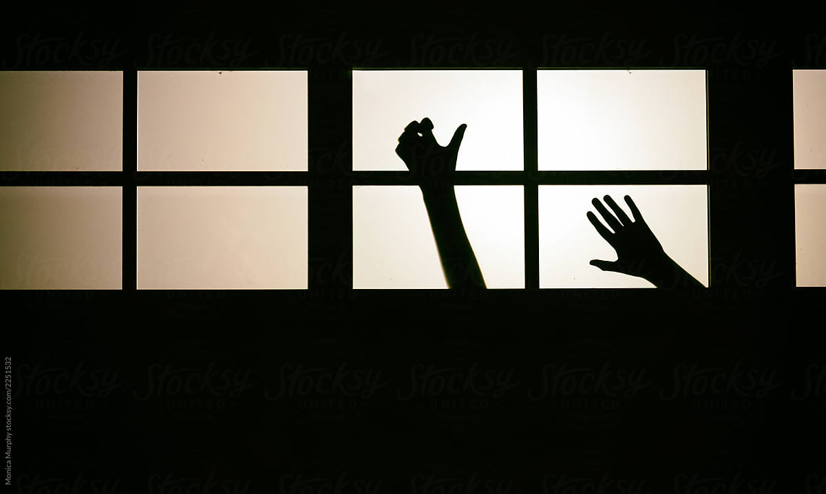 Silhouette of creepy hands in window at night