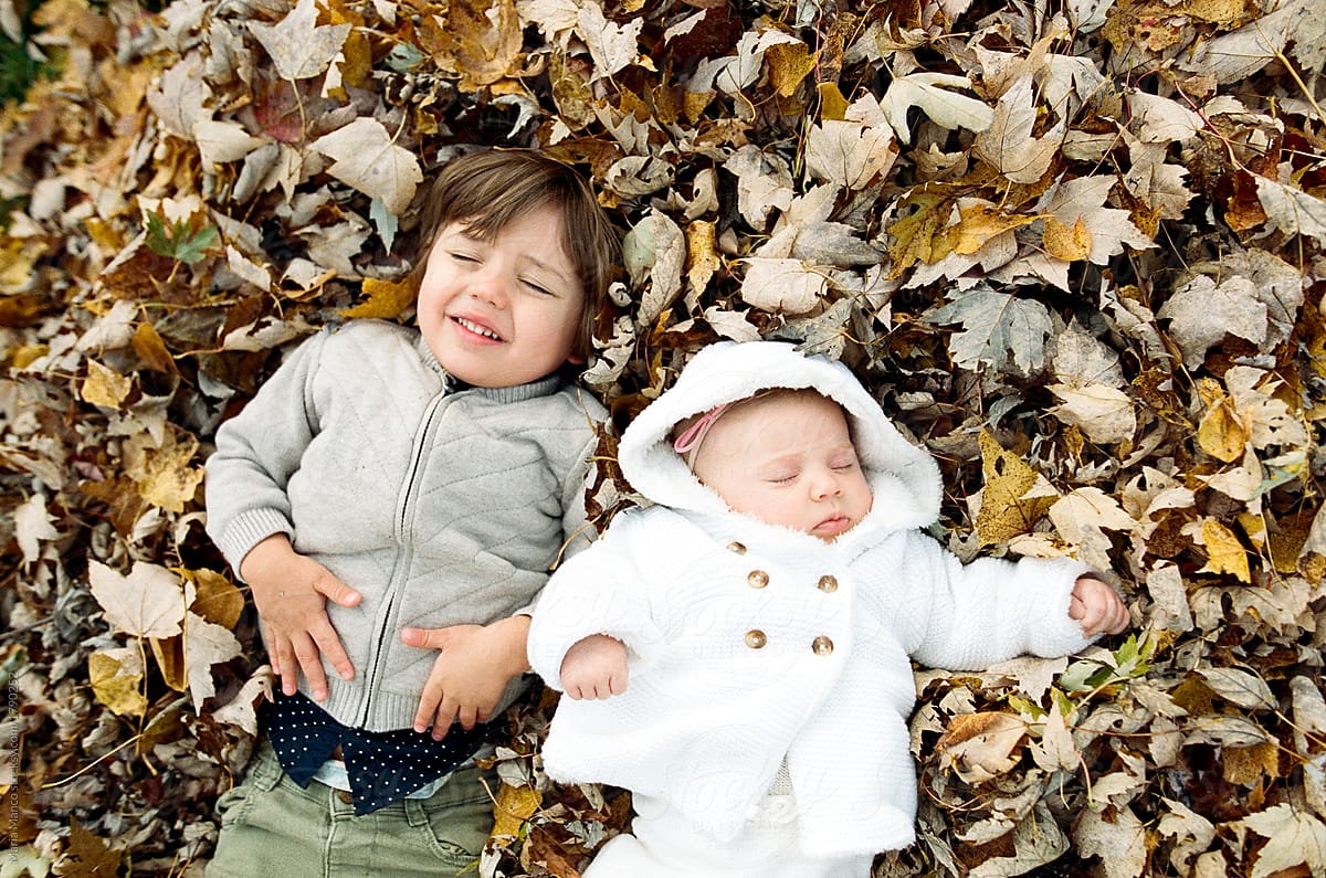 siblings lay in leaf pile