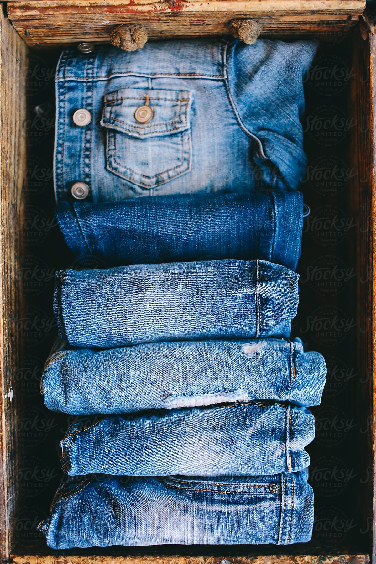 Selection of blue denim clothing in a wooden box