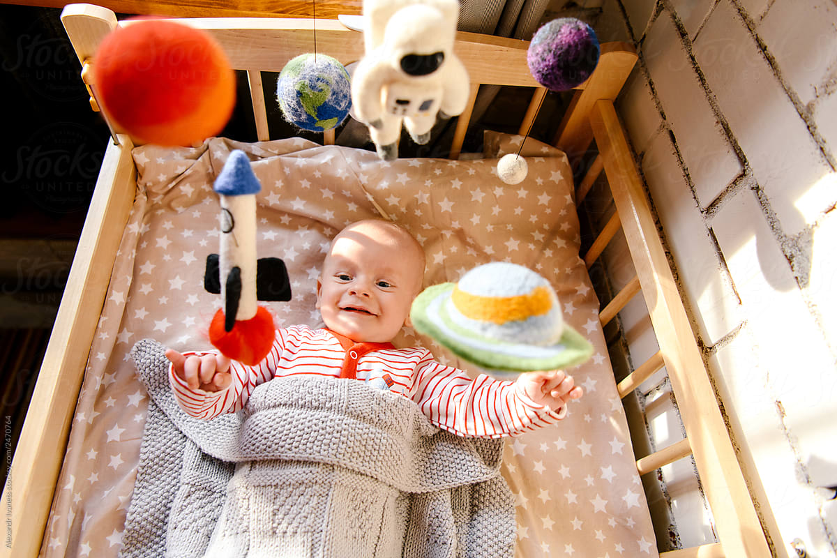 Funny baby in infant bed with mobile