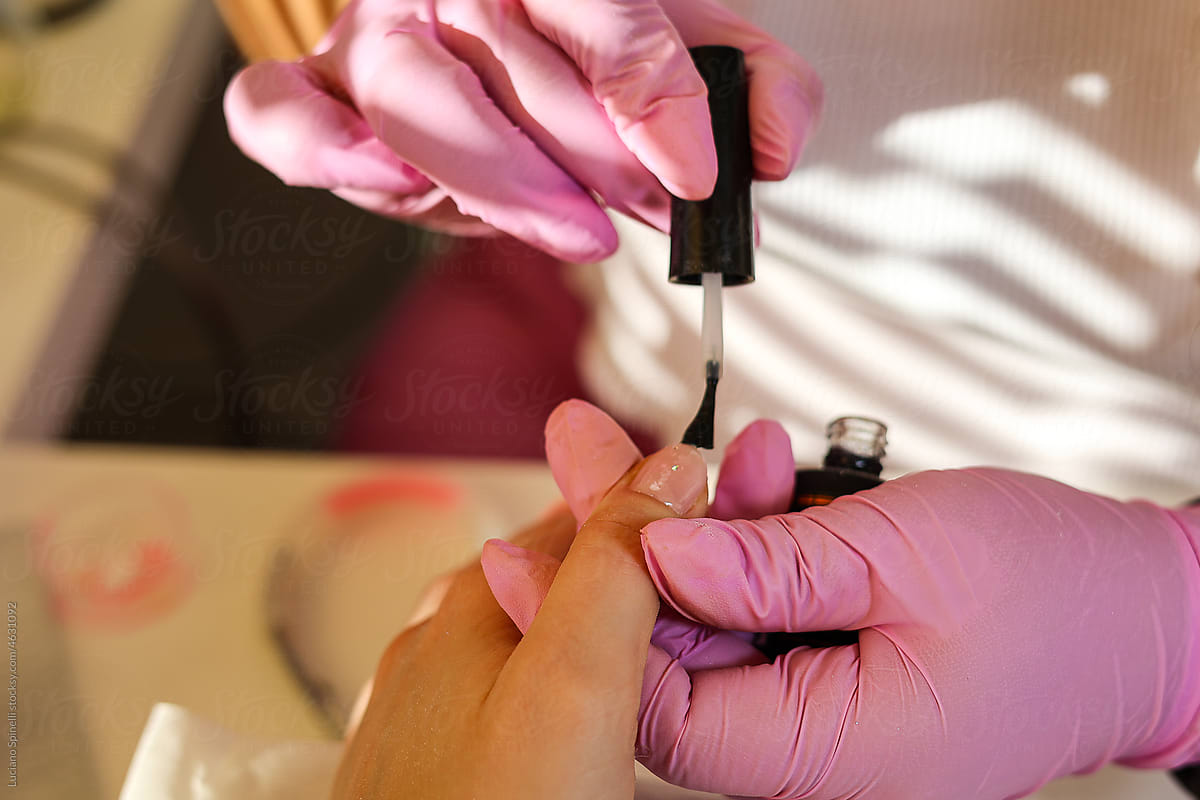 A manicurist covers woman's nails with a nail polish in a nail salon
