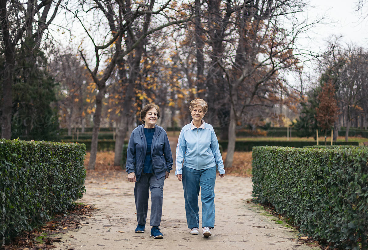 Two senior women in sportswear walking and exercising in a park