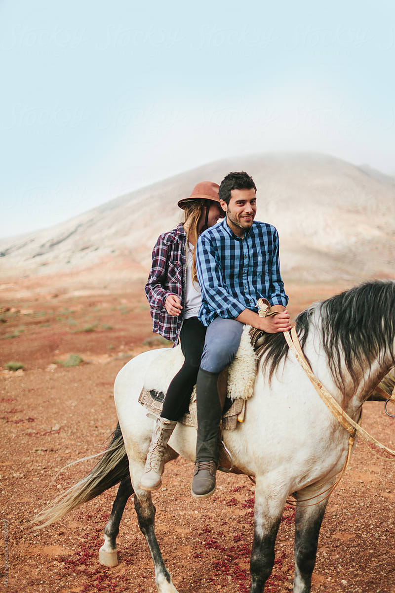 Young Couple riding a White Horse in the Desert
