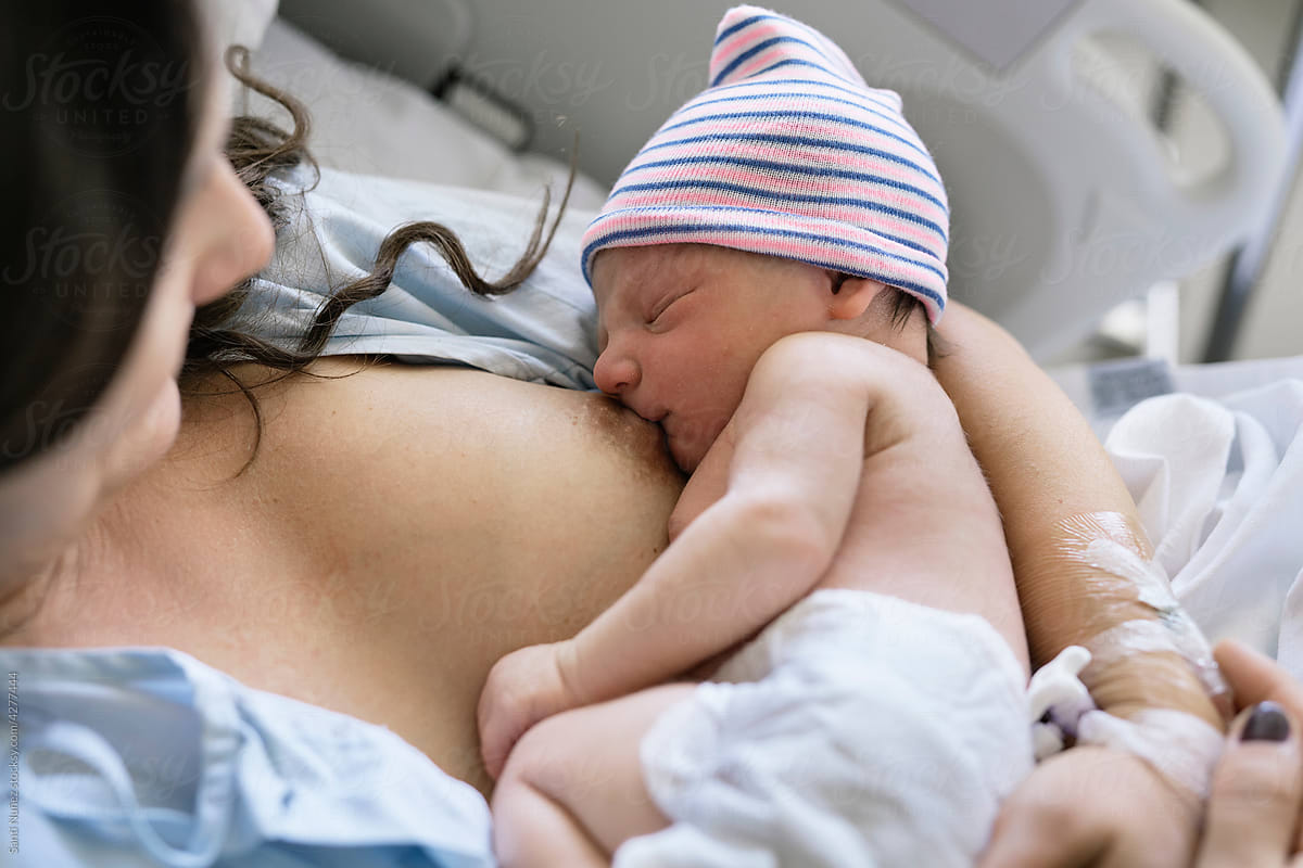 Young woman Breastfeeding Newborn In Hospital