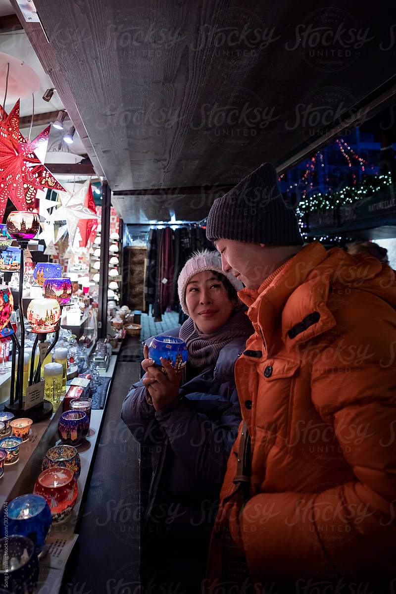 Happy couple in warm clothes enjoying colorful Christmas market