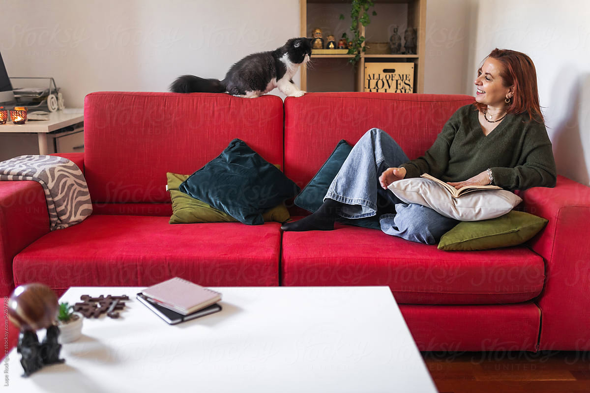 mature woman with her persian cat reading a book at home