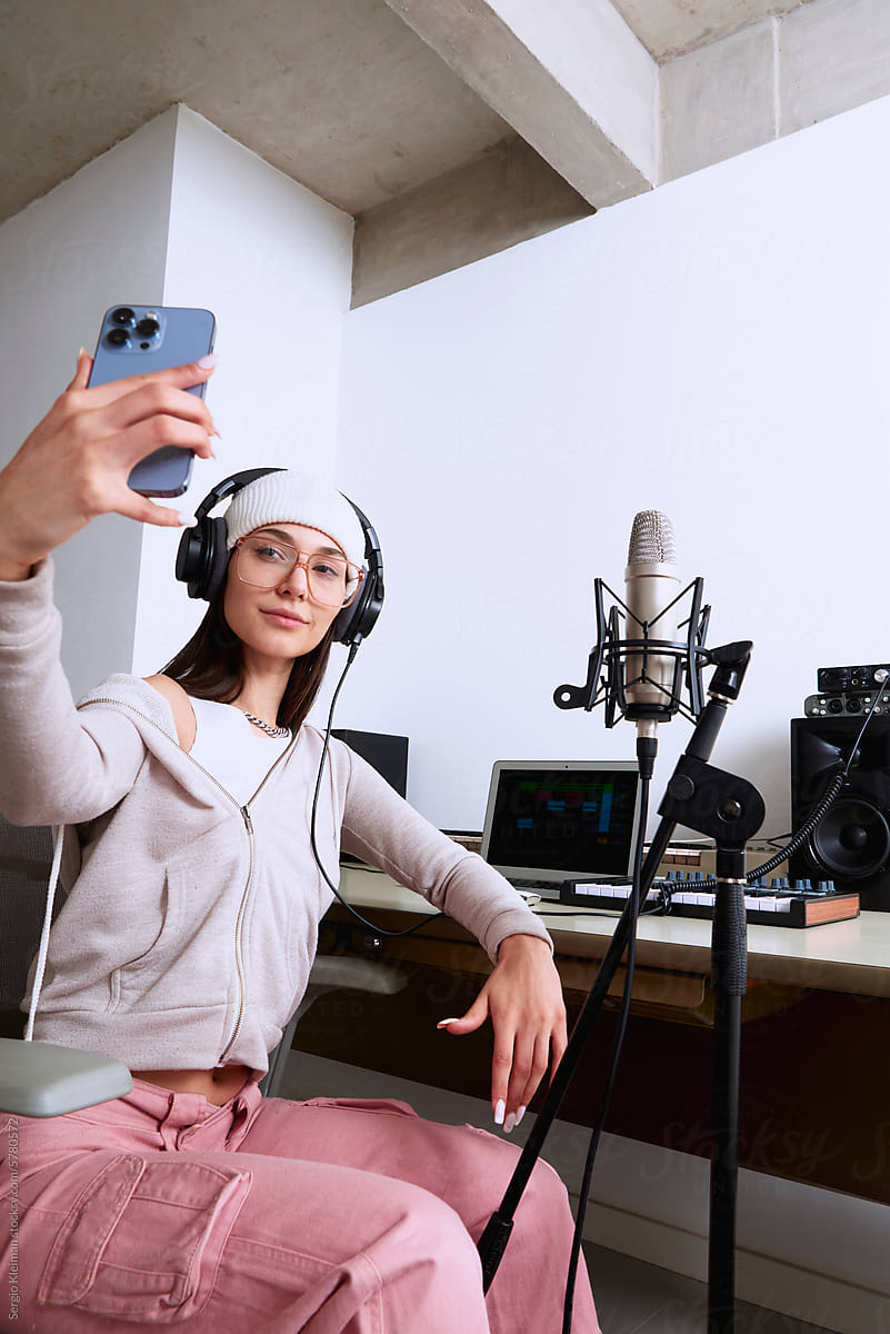 Young female musician taking a selfie in her home studio.