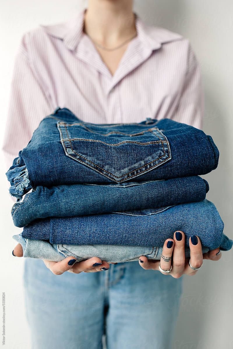 Crop woman with a stack of jeans for upcycling