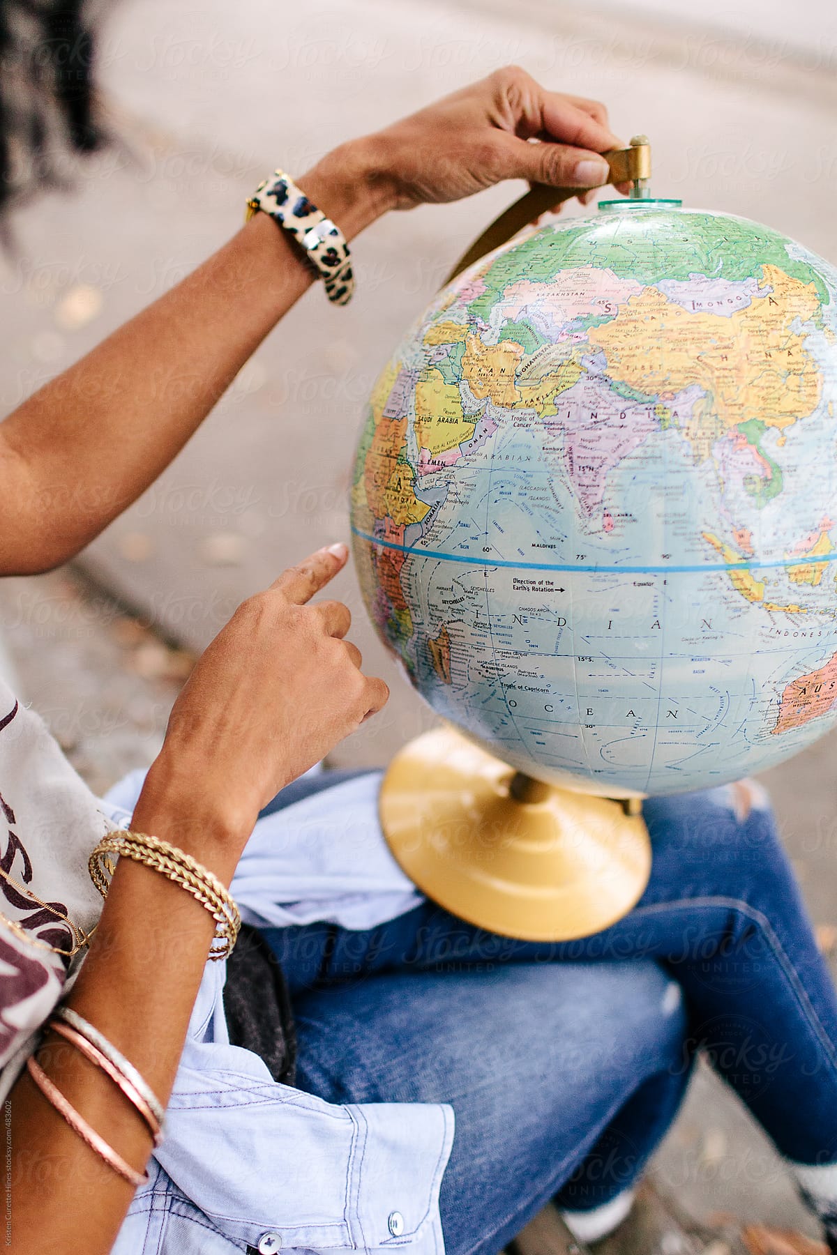 A woman pointing at a location on a world globe