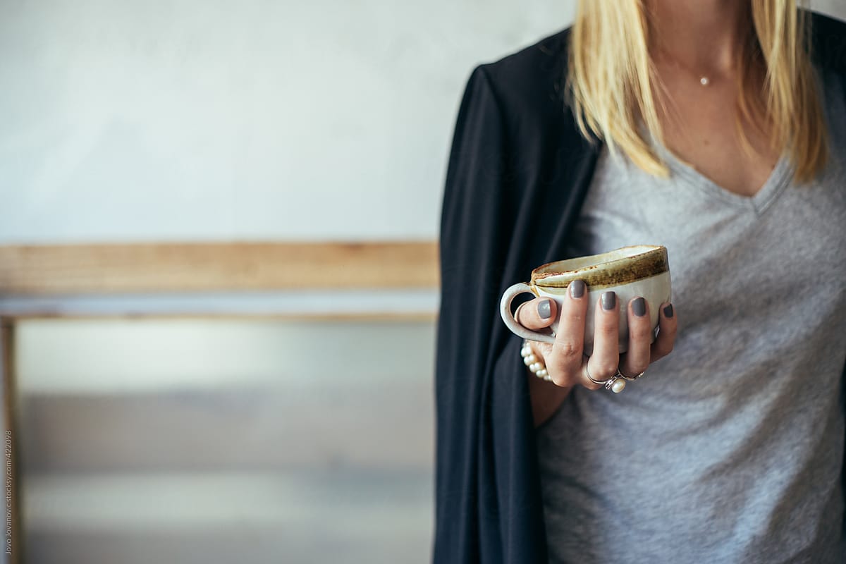 Close up on blonde woman hands holding cup of coffee