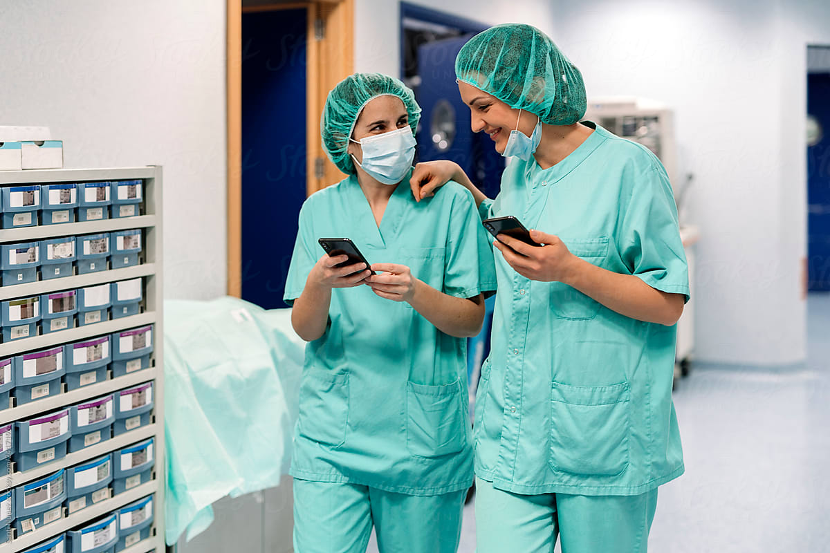 Female doctors in uniforms and masks using smartphones