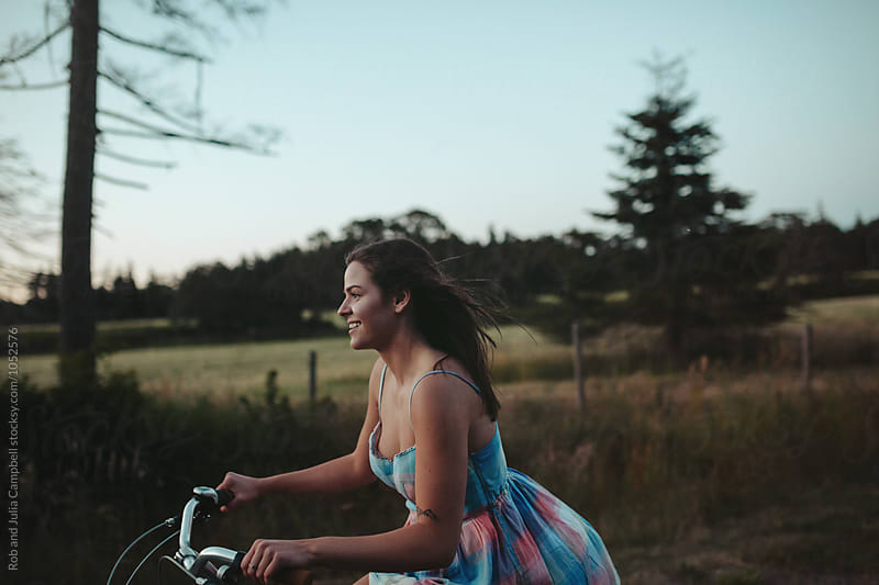 Young happy caucasian girl riding cruiser bike on country road