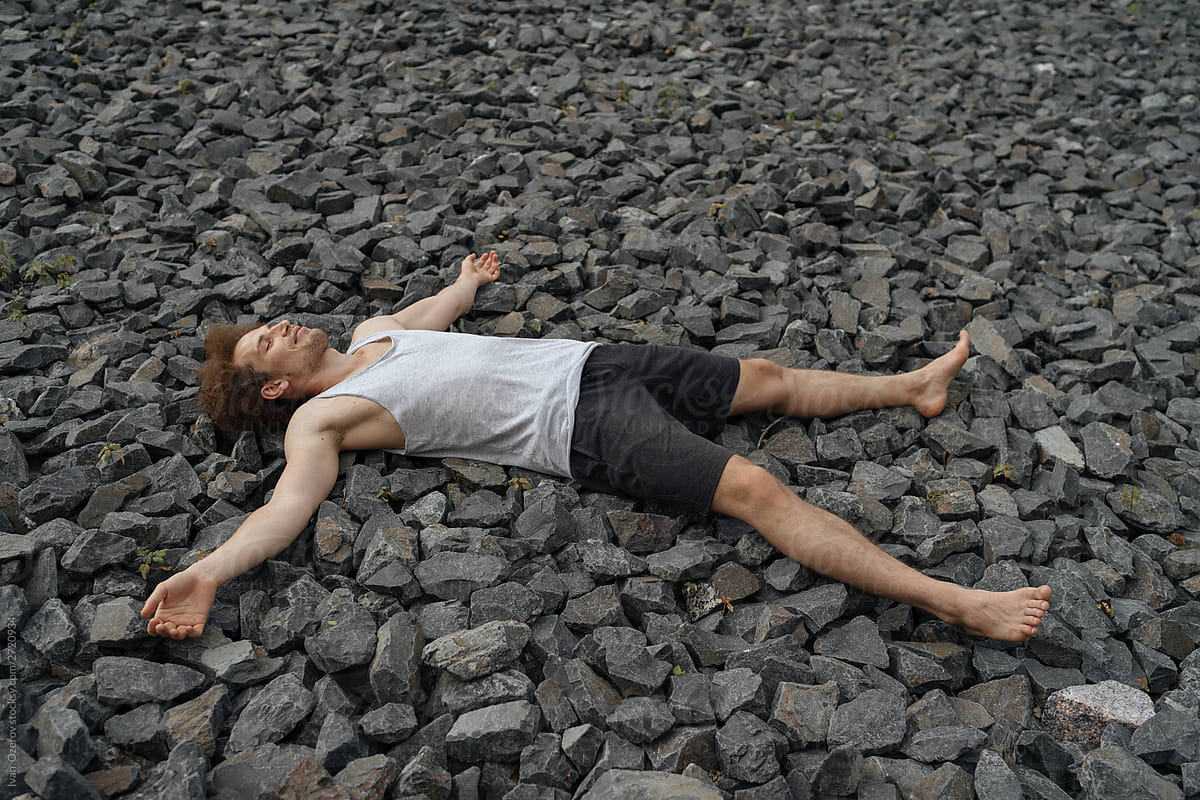 Relaxed guy lying on stony ground