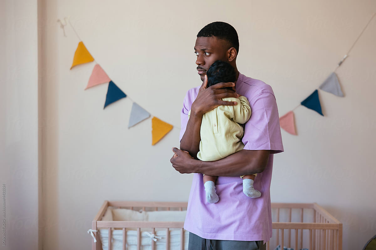 African American father with baby in nursery room