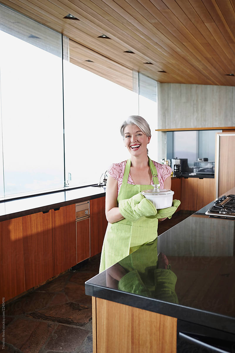 Mature woman with grey hair holding a baking dish