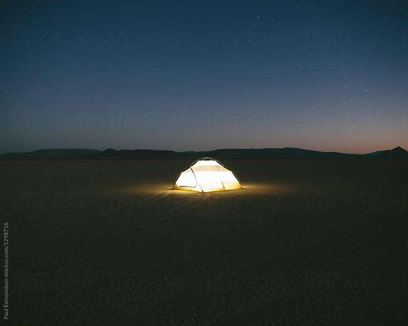 Illuminated camping tent on playa at dusk