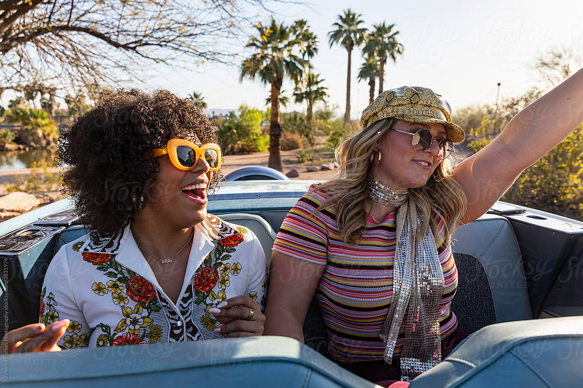 Happy Friends riding in the back of Convertible car in Arizona with palm trees