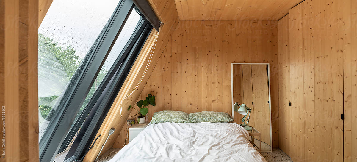 Modern bedroom interior covered with timber and a big geometric window