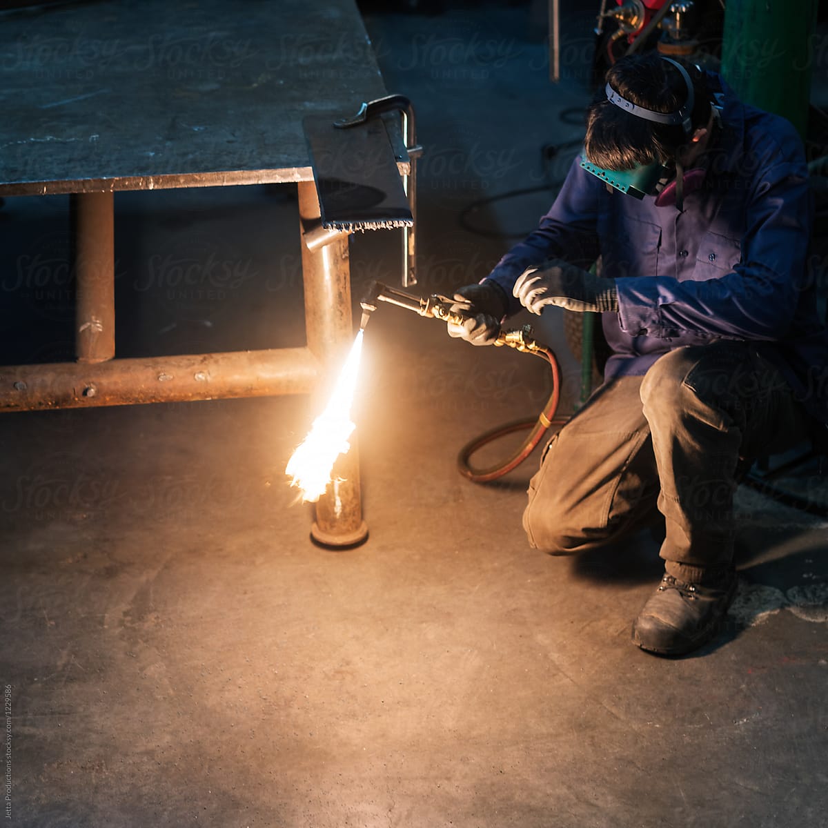 Factory worker adjusts his welding torch