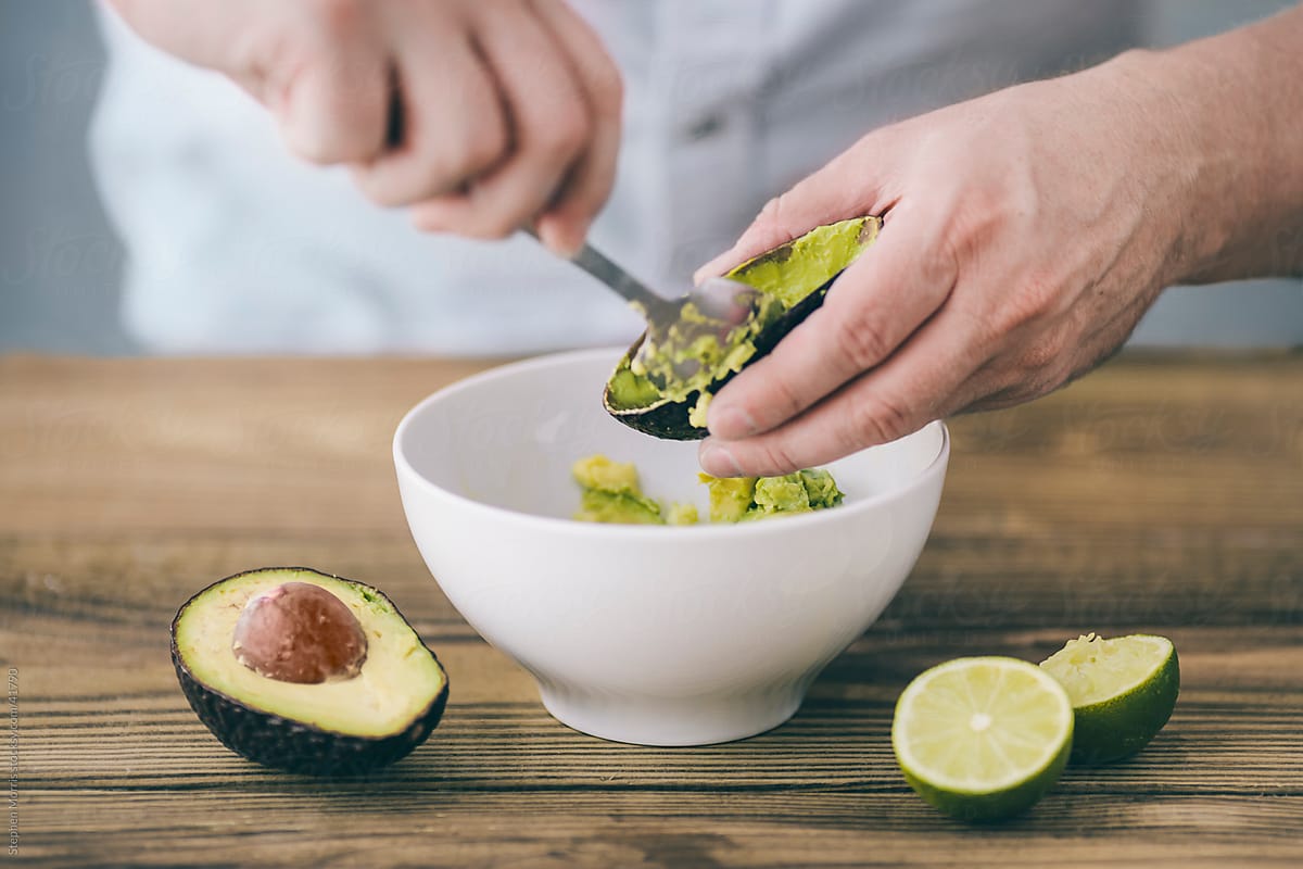 Man Preparing Guacamole with Avocados and Lime