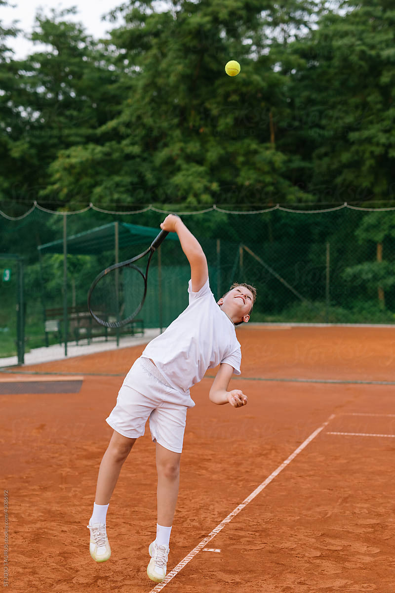 Young boy on a tennis court playing tennis