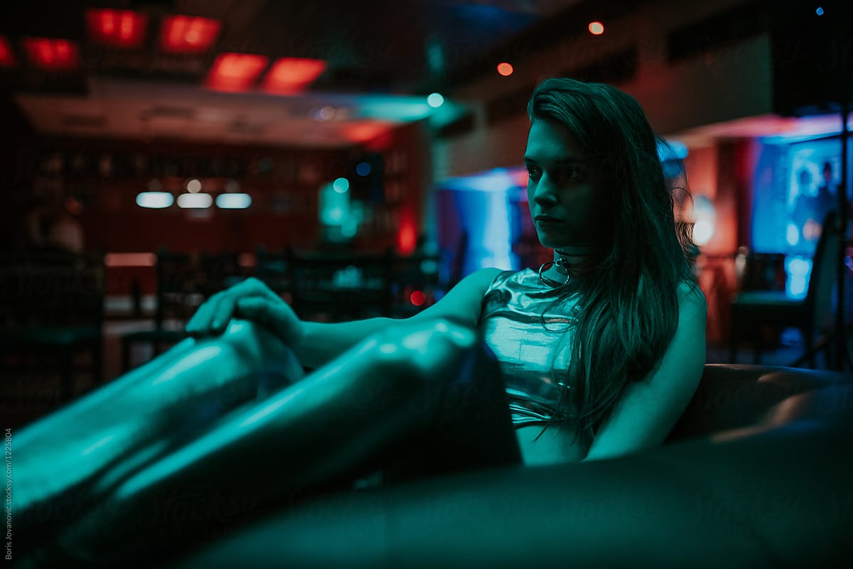 Close up of a young woman in shiny outfit sitting in the club