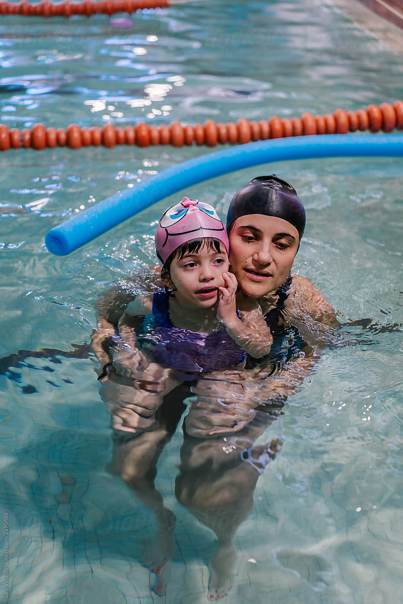 Little Girl Swimming With Her Mum In A Indoor Pool.