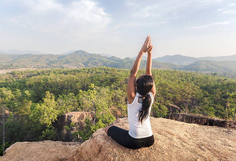 Woman in yoga position overlooking mountain landscape