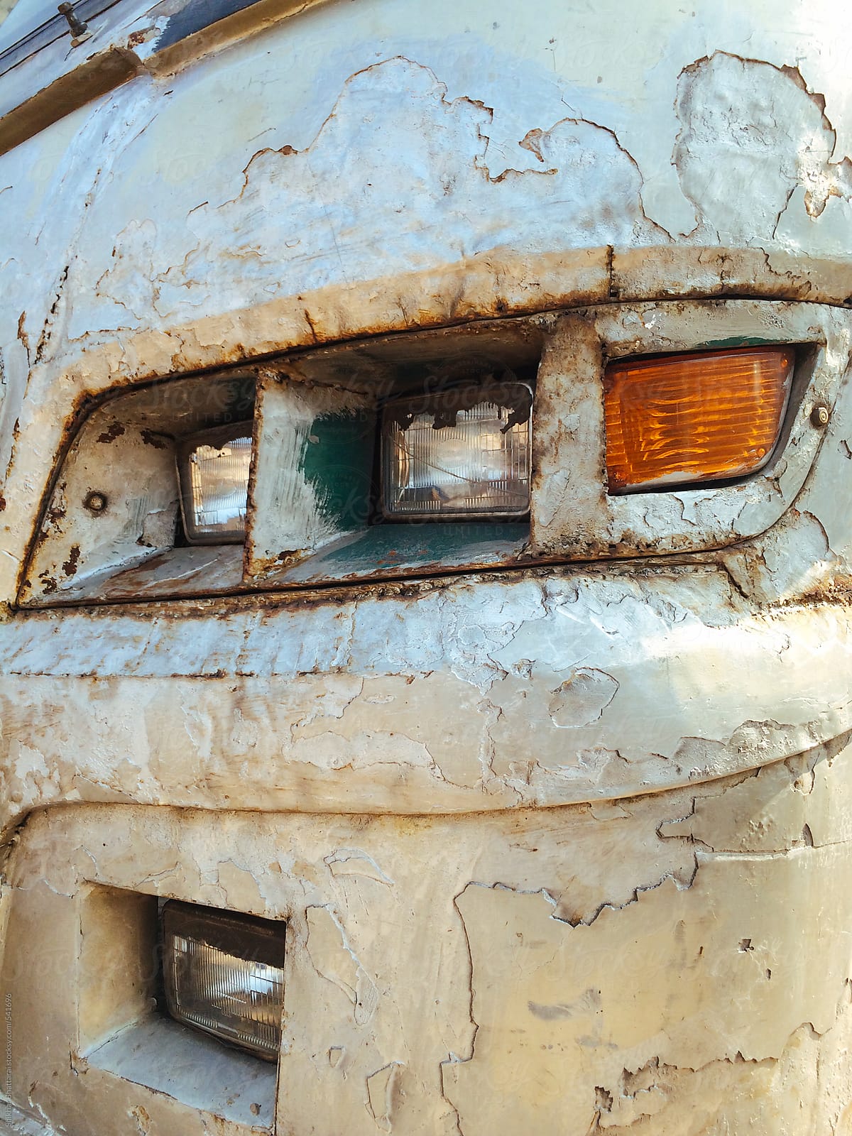 A banged up and reconstructed headlights of a bus.