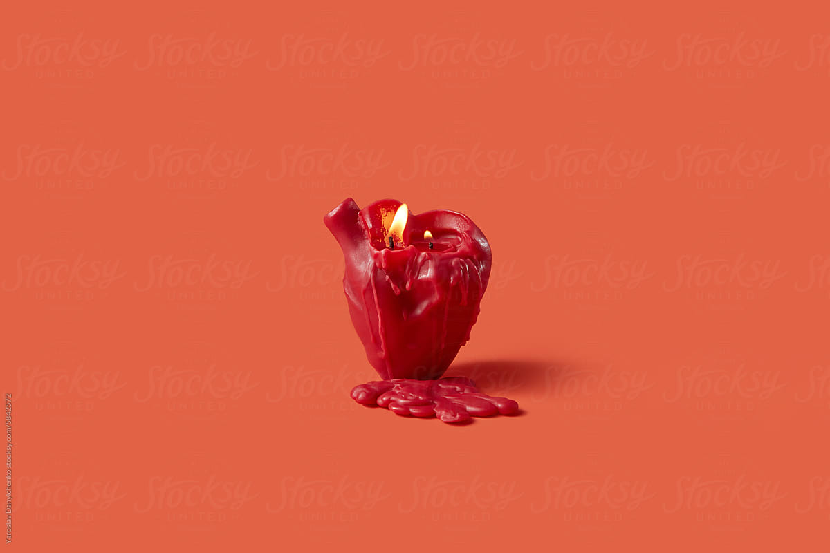 Creative burning candle in human heart shape over red background