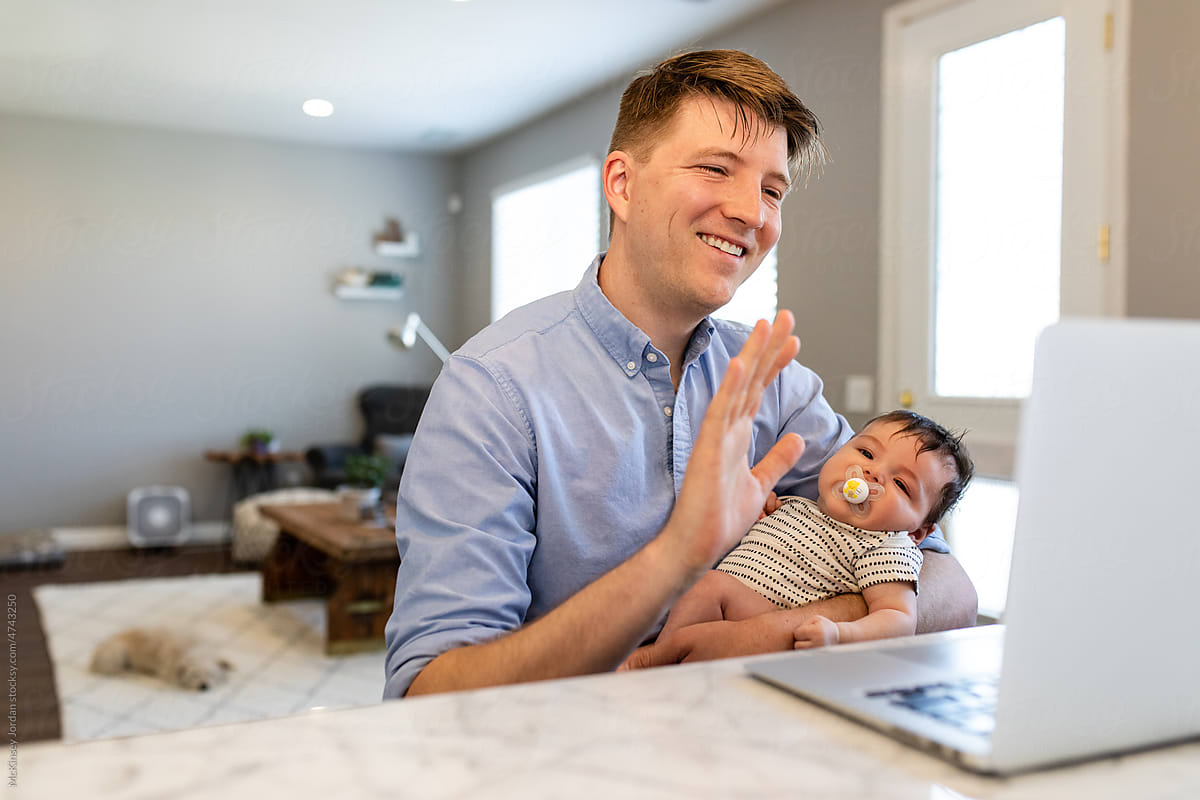 Man Waves While On A Video Call While Holding A Baby
