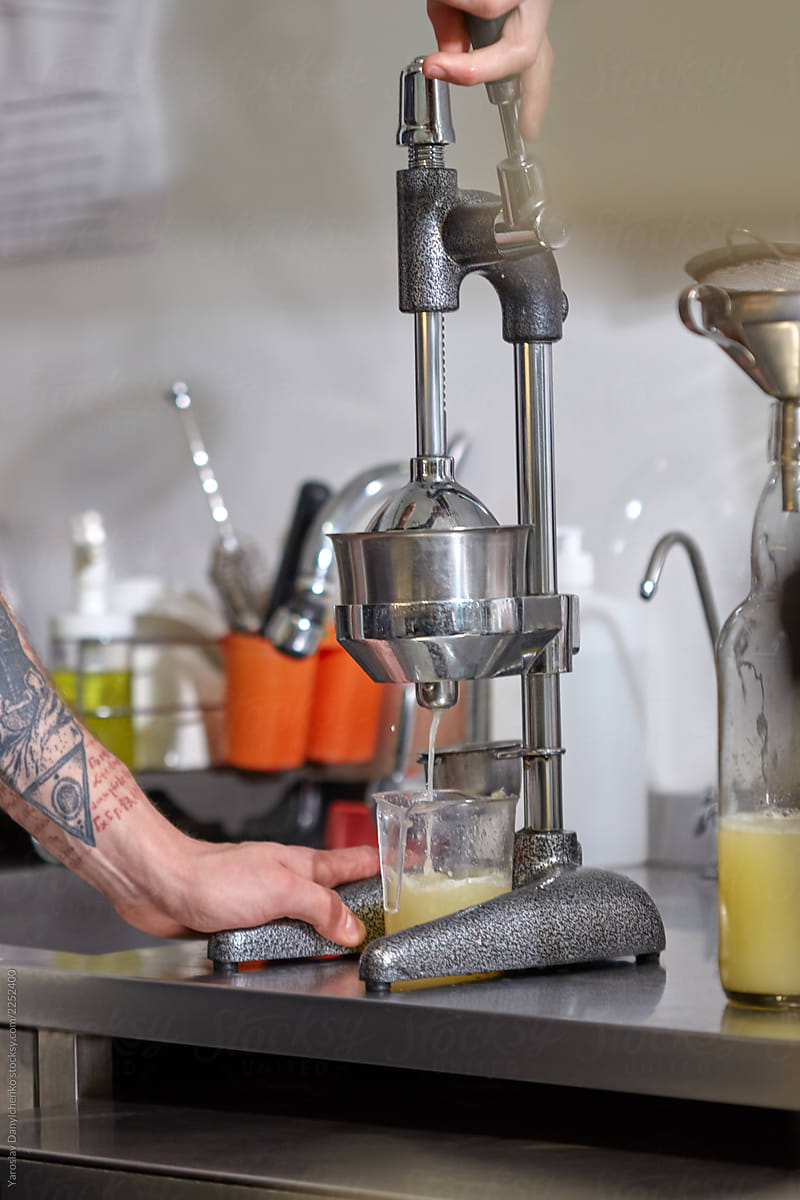 Process of preparation squeezing citrus juice. Man make lemon juice into glass on a kitchen table.