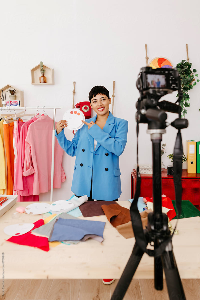 Cheerful female fashion blogger recording video on camera
