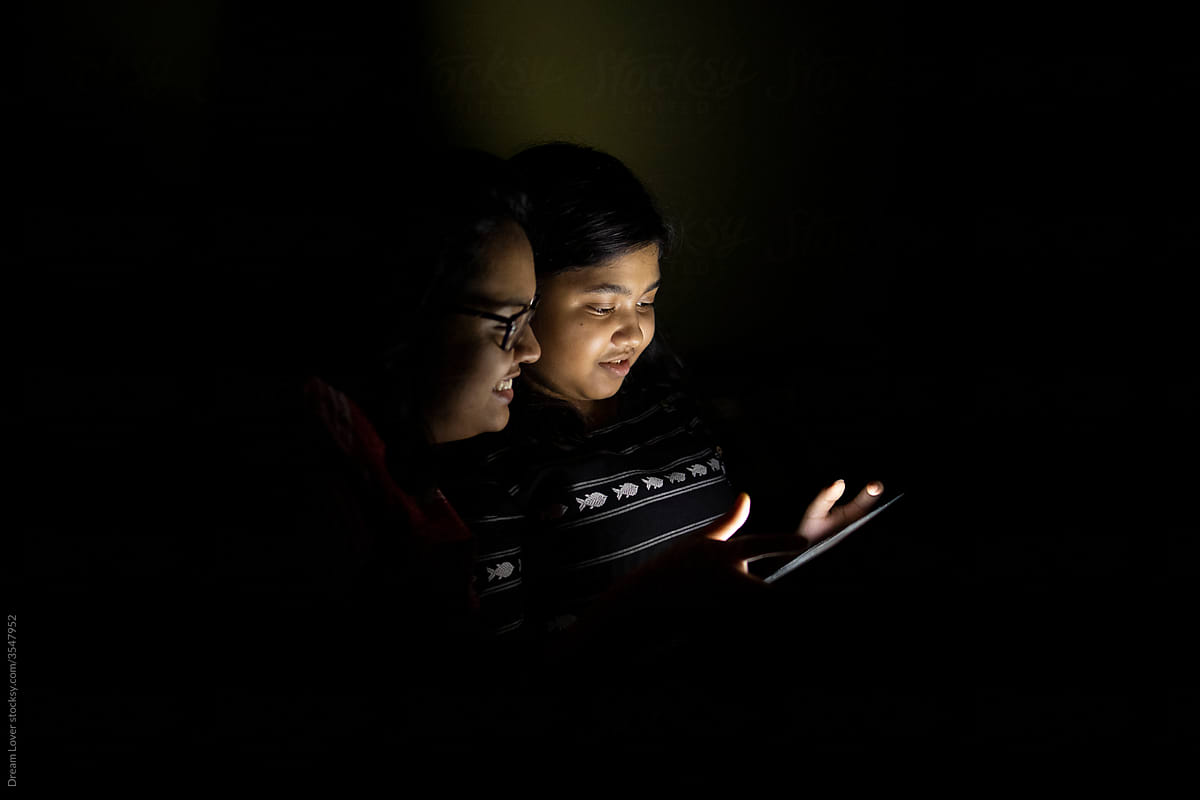 Sisters watching movie in a tablet/laptop inside house at night