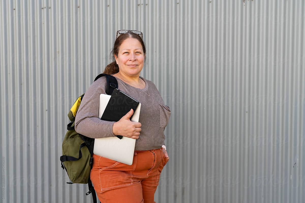 Woman standing with laptop, backpack and notebook