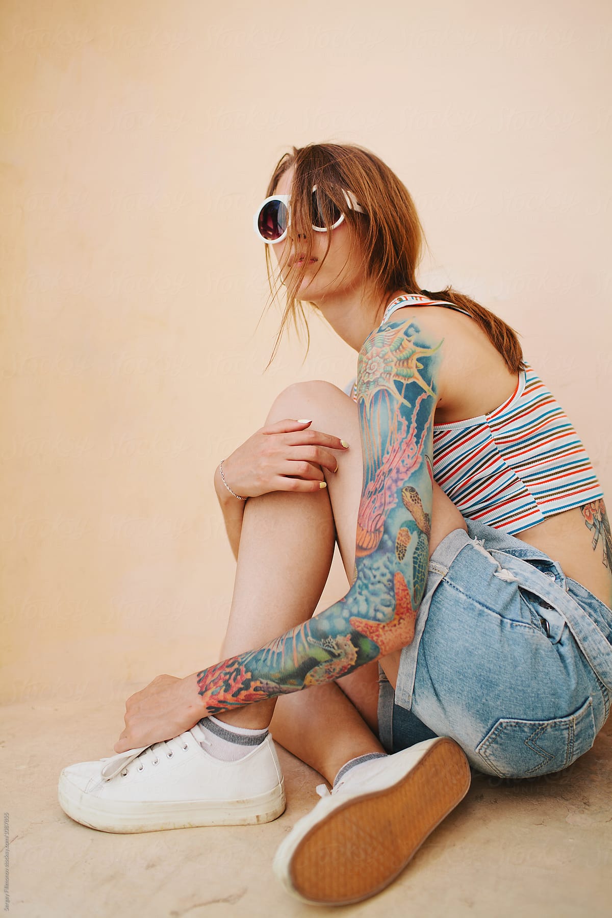 Trendy tattooed model sitting in niche