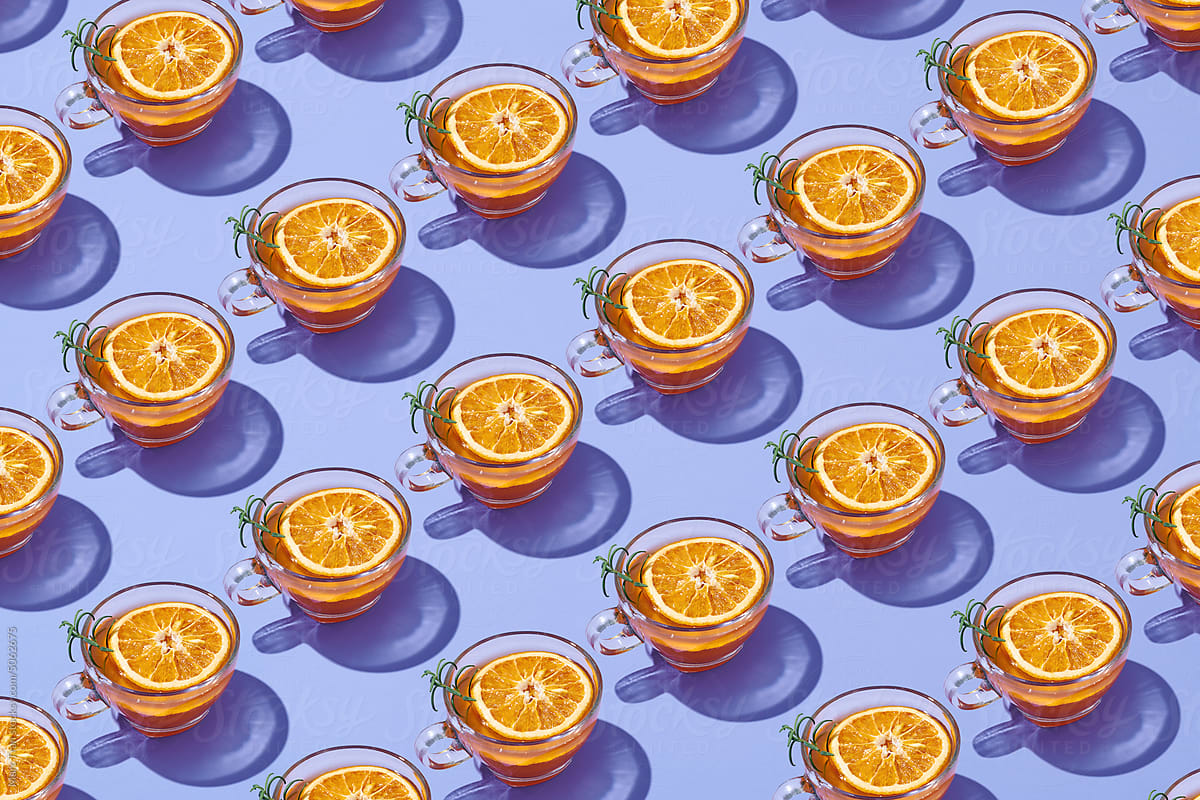 Pattern of tea with orange in transparent mug and sun glare.