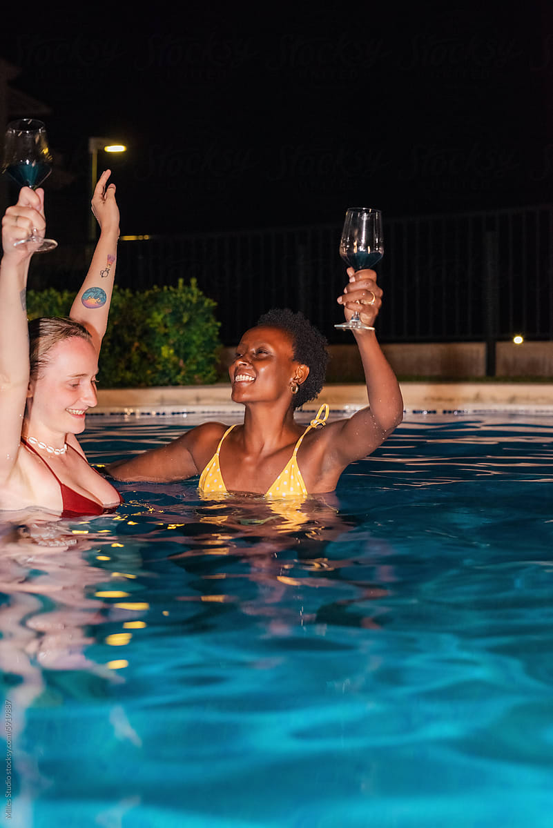 Happy women celebrating at night pool party